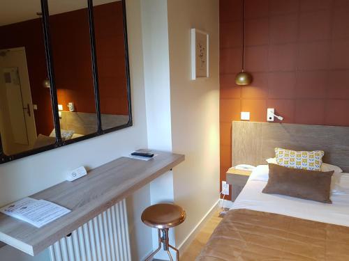 a bedroom with a bed and a mirror and a stool at Les Chants d'Ailes - Hôtel Face Mer in La Turballe