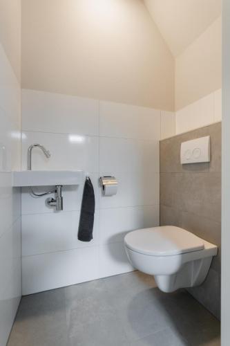 a white bathroom with a toilet and a sink at Vakantiewoning Seaside, Burgvliet 11 in Oostkapelle
