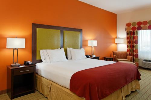 1 cama grande en una habitación de hotel con paredes de color naranja en Holiday Inn Express Florence Northeast, an IHG Hotel, en Florence