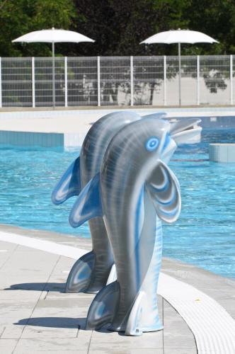 a statue of a dolphin in front of a pool at Club del Sole Adriano Family Collection in Punta Marina