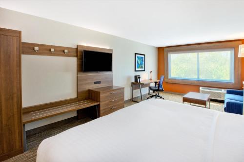 a hotel room with a bed and a flat screen tv at Holiday Inn Express & Suites New Castle by IHG in New Castle
