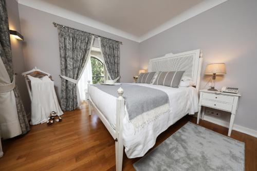 a bedroom with a white bed and a window at Grande Hotel das Caldas da Felgueira in Caldas da Felgueira