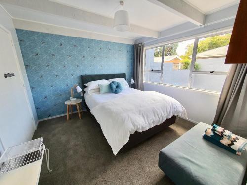 - une chambre dotée d'un lit avec un mur bleu dans l'établissement Little Glennie - Blenheim Holiday Home, à Blenheim
