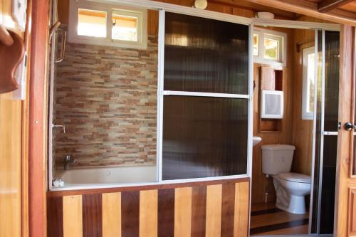 a bathroom with a window and a tub and a toilet at Hilamito Lodge in Tela