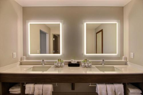 a bathroom with two sinks and two mirrors at Holiday Inn Express & Suites Fond Du Lac, an IHG Hotel in Fond du Lac