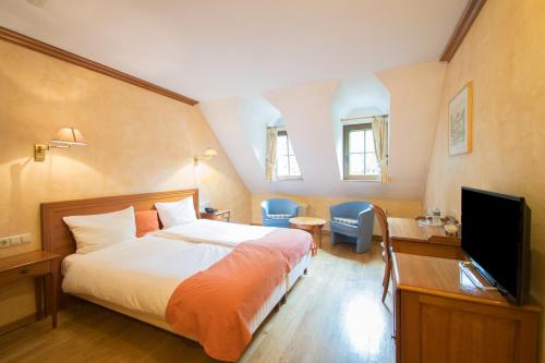 1 dormitorio con 1 cama y TV de pantalla plana en Aux Tanneries de Wiltz, en Wiltz