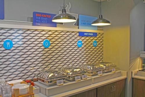 a kitchen with a row of silver pans on a wall at Holiday Inn Express & Suites - St. Louis South - I-55, an IHG Hotel in Mattese