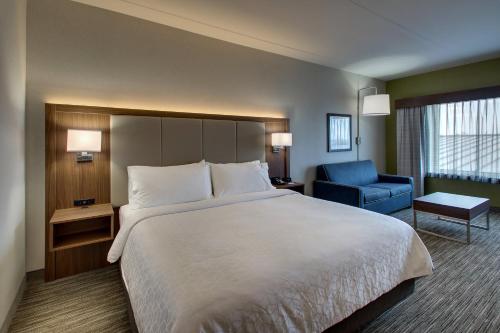 a hotel room with a large bed and a blue chair at Holiday Inn Express & Suites Findlay North by IHG in Findlay