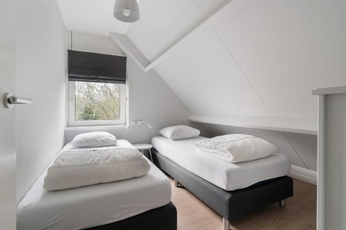 twee bedden in een kamer met een raam bij vakantiehuis Seaside, Dunoweg 18 in Oostkapelle