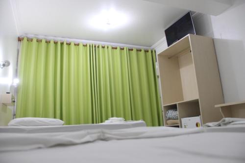 a bedroom with a green curtain and two beds at Oasis Chartouni Hotel in Blumenau