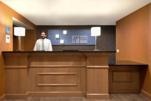 a man standing at a reception desk in a hotel room at Holiday Inn Express Hotel & Suites Fraser Winter Park Area by IHG in Fraser