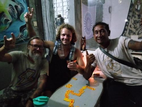 a group of three men sitting at a table with a cake at Apollo Hostel in Lovina