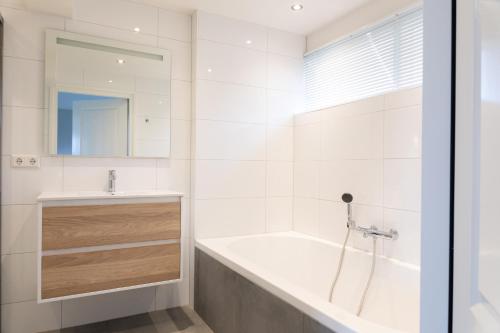 a white bathroom with a tub and a sink at Ruyge Weyde Logies - The Farmers Daughter in Oudewater