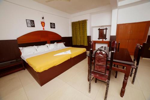 a bedroom with a large bed with a desk and a yellow blanket at Kairali Tourist Home in Guruvāyūr