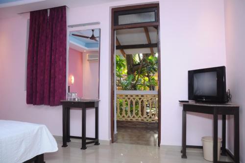 a room with a television and a door with a window at Palolem Guest House in Palolem