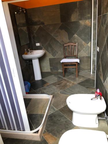 uma casa de banho com um lavatório, um WC e uma cadeira. em Bed & Breakfast 101 em Galatina