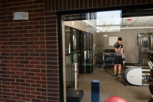 a man standing in a gym looking at his cell phone at Holiday Inn Express & Suites Oklahoma City Downtown - Bricktown by IHG in Oklahoma City