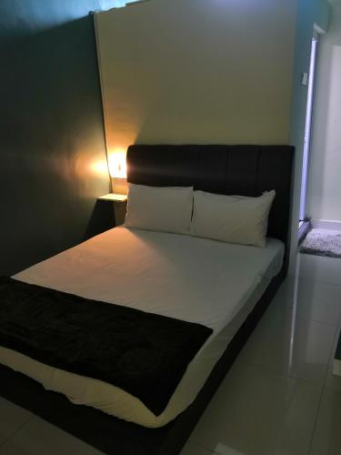 a bed with a black headboard and white sheets and pillows at WeJDAN INN BALIK PULAU, PENANG ISLAND in Balik Pulau