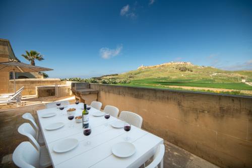 a white table with white chairs and a view of a hill at Rebekah Holiday Home in Għasri