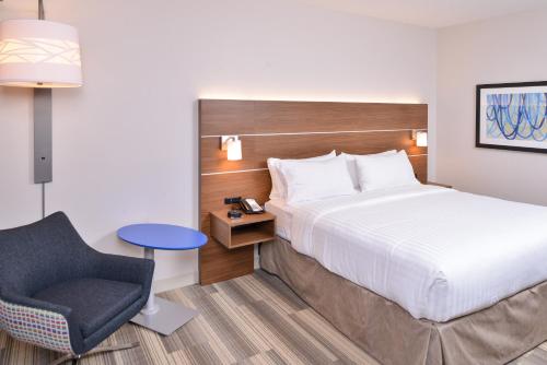 a hotel room with a bed and a chair at Holiday Inn Express & Suites Indianapolis Dtn-Conv Ctr Area by IHG in Indianapolis