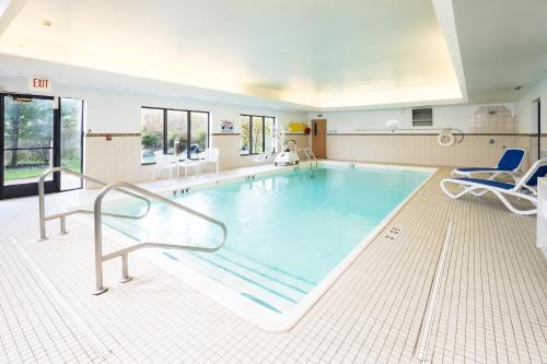 a large swimming pool with two chairs at Holiday Inn Express Hotel & Suites Grand Blanc, an IHG Hotel in Grand Blanc
