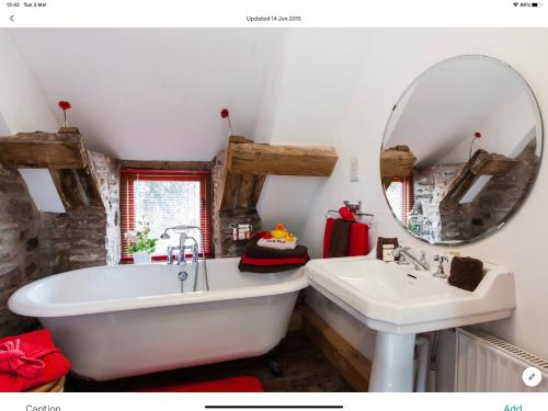 La salle de bains est pourvue d'une baignoire, d'un lavabo et d'un miroir. dans l'établissement Ty Fferm Hen, The Ancient Farmhouse, à Talybont