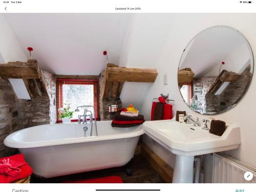 a bathroom with a tub and a sink and a mirror at Ty Fferm Hen, The Ancient Farmhouse in Talybont