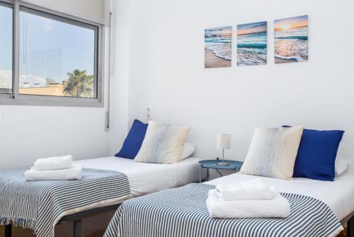 two beds in a room with a window at Lodging Apartments Beach Apartment Villa Olimpica in Barcelona