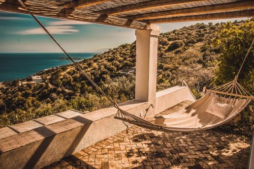 a hammock on a porch overlooking the ocean at Villa Von Sophia / THE HOUSE in Áyioi Apóstoloi