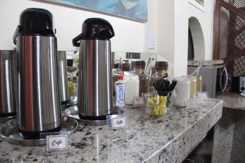 a counter with two silver kettles on top of it at Oasis Chartouni Hotel in Blumenau