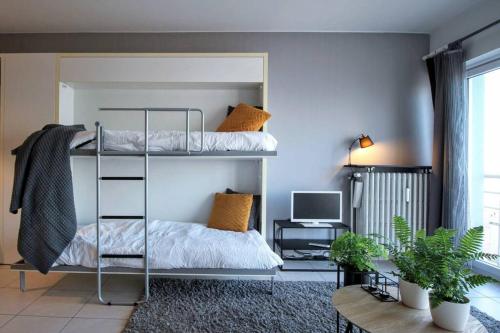 a bedroom with two bunk beds and a television at Knappe studio met subliem zeezicht! in Ostend