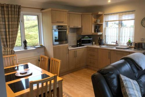 a kitchen with a table and a couch and a table and chairs at SOLACE COTTAGE in Bunavoneader