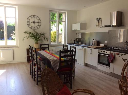 une cuisine avec une table et des chaises et une horloge au mur dans l'établissement Logis de Villemaurine, à Saint-Émilion