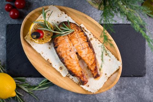 a wooden plate with a piece of fish on it at Sobi Hotel in Vyshhorod