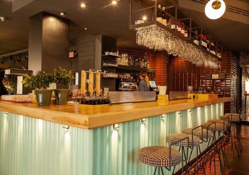 a bar with stools and a woman behind a counter at Sixties Ramblas in Barcelona
