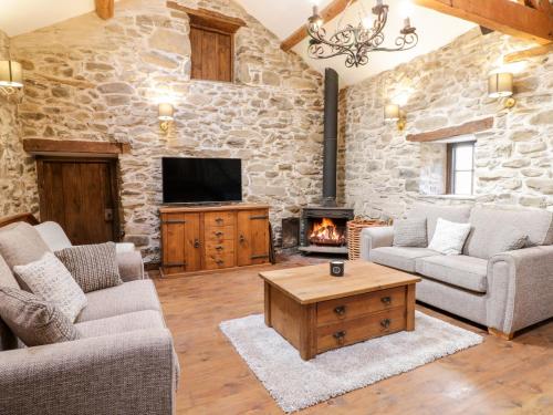 a living room with a stone wall and a fireplace at Groes Heol in Machynlleth