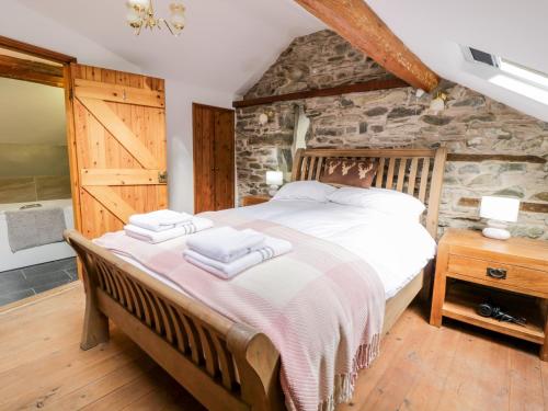 a bedroom with a bed and a stone wall at Groes Heol in Machynlleth