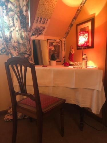 a table with a chair and a white table cloth at La Maison de juliette in Saint-Hippolyte