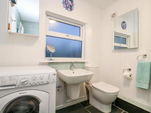 ein Badezimmer mit Waschmaschine und Waschbecken in der Unterkunft Rosa Cottage in Porthleven