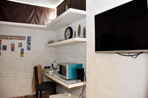 a room with a desk with a microwave and a television at Design House Corrientes in Corrientes