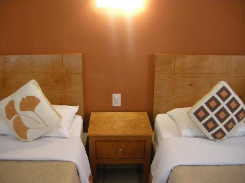 een kleine kamer met 2 bedden en een houten tafel bij Hotel Posada Real in Lagos de Moreno