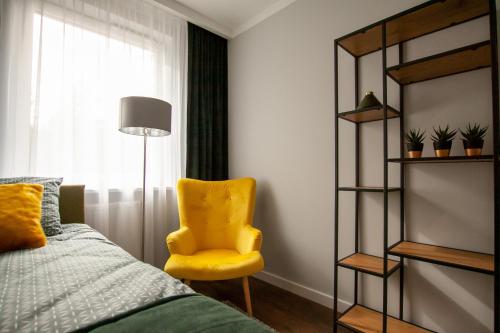 een slaapkamer met een gele stoel naast een bed bij Apartament Leśny No 5 Green ,garaż w cenie in Kielce