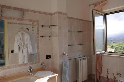a bathroom with a sink and a shower with a robe at Villino Lenci in Trappitello