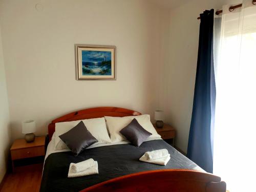 a bedroom with a bed with two pillows on it at Apartments Dolac in Sveti Filip i Jakov