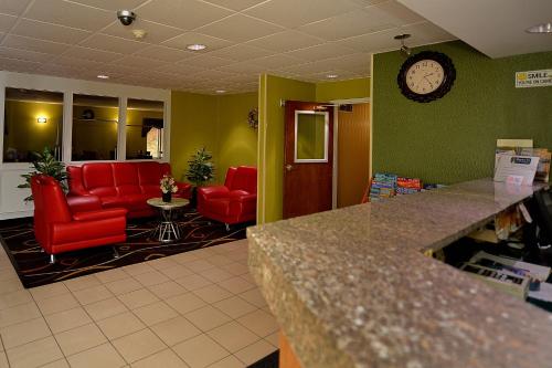 a waiting room with red chairs and a clock on the wall at Baymont by Wyndham North Dartmouth Fall River in North Dartmouth