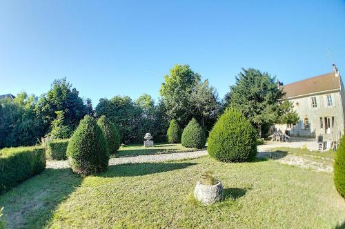 un jardin avec des arbres et des buissons devant un bâtiment dans l'établissement Gîte Jura Lac Emeraude, à Clairvaux-les-Lacs