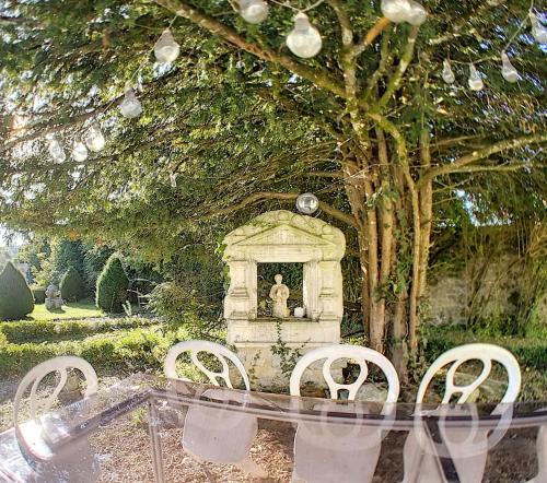 a table and chairs under a tree with a statue at Gîte Jura Lac Emeraude in Clairvaux-les-Lacs