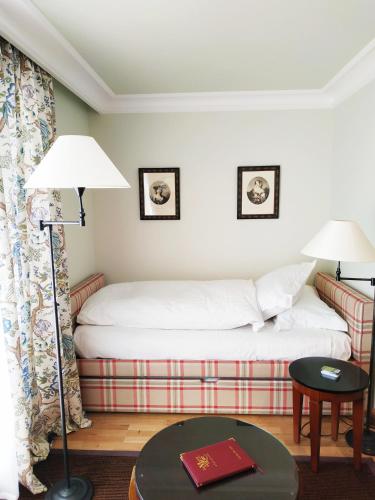 a bedroom with a bed and a table and a lamp at Le Manoir Au Lac in Gérardmer