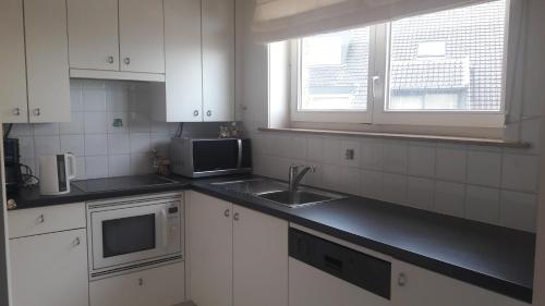 a kitchen with white cabinets and a sink and a window at Belvedere 2.3 in Blankenberge