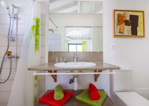 a bathroom with a sink and red and green towels at Iguane House Villas & Micro Spa in Sainte-Anne